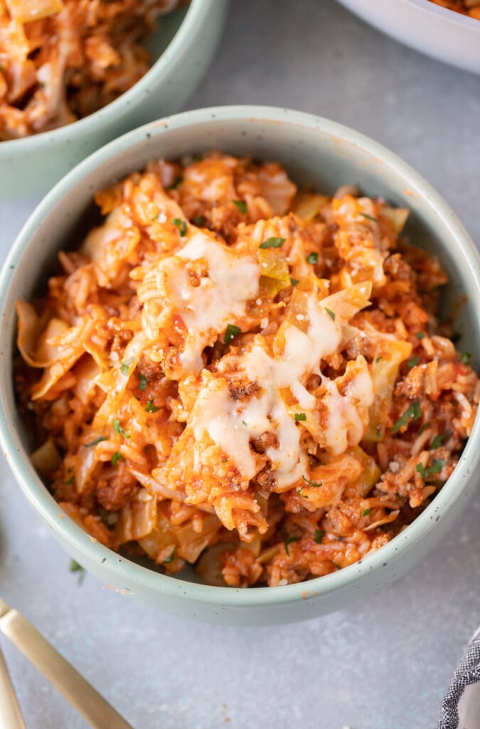 An overhead shot of an unstuffed cabbage rolls recipe in a bowl with another bowl on the side on a grey background