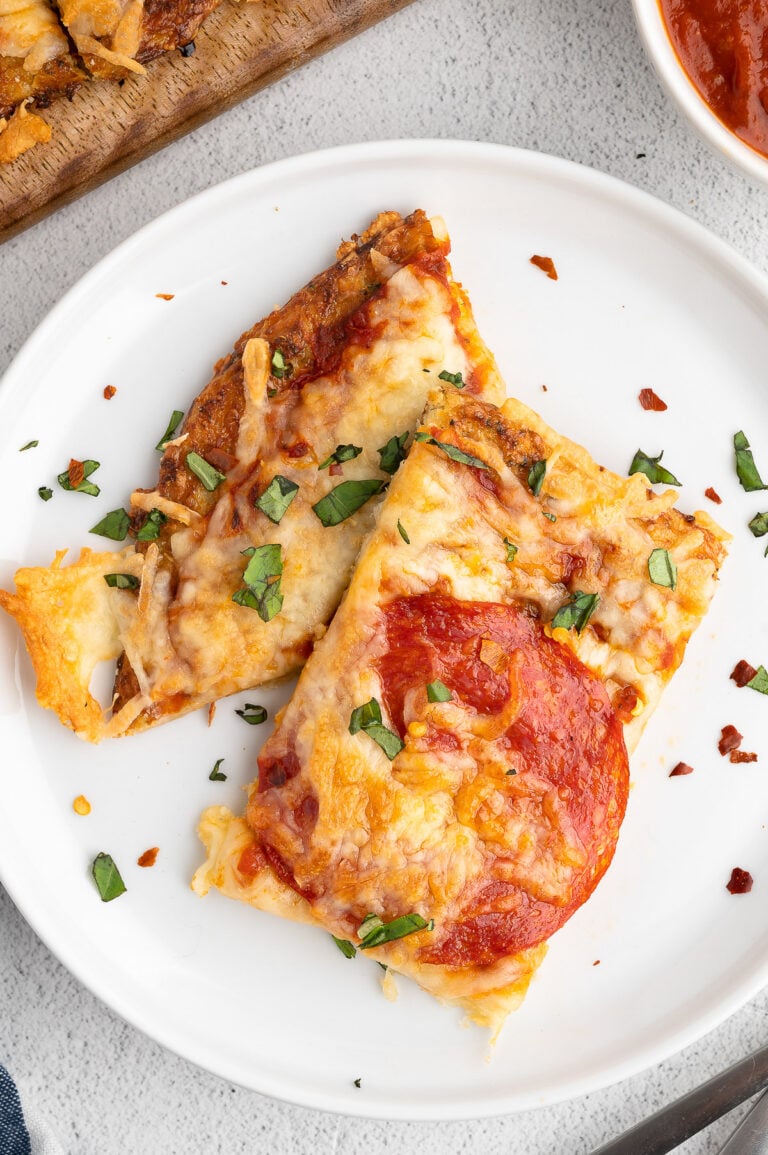 A white plate with two pieces of keto pizza with cauliflower pizza crust