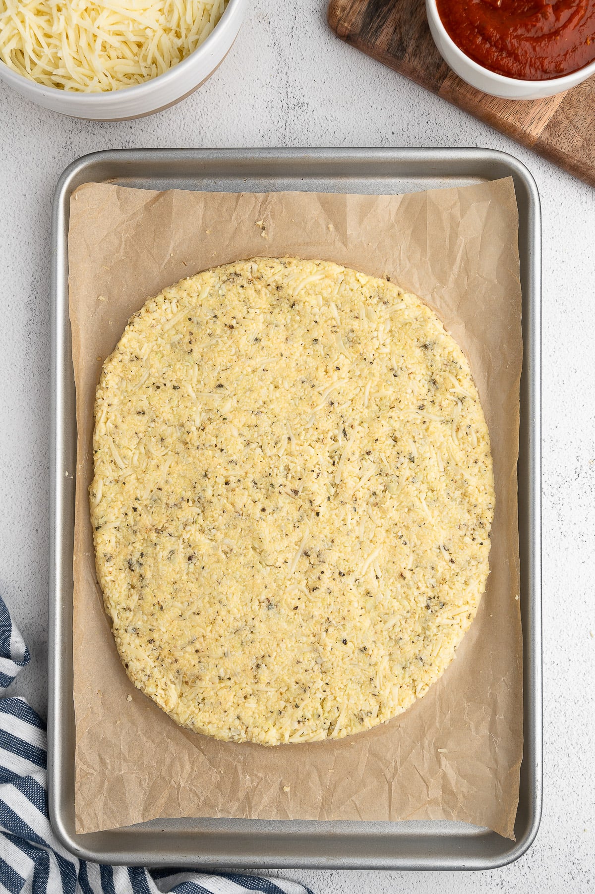 A cauliflower pizza crust before being cooked on a baking sheet on a white background cauliflower pizza dough
