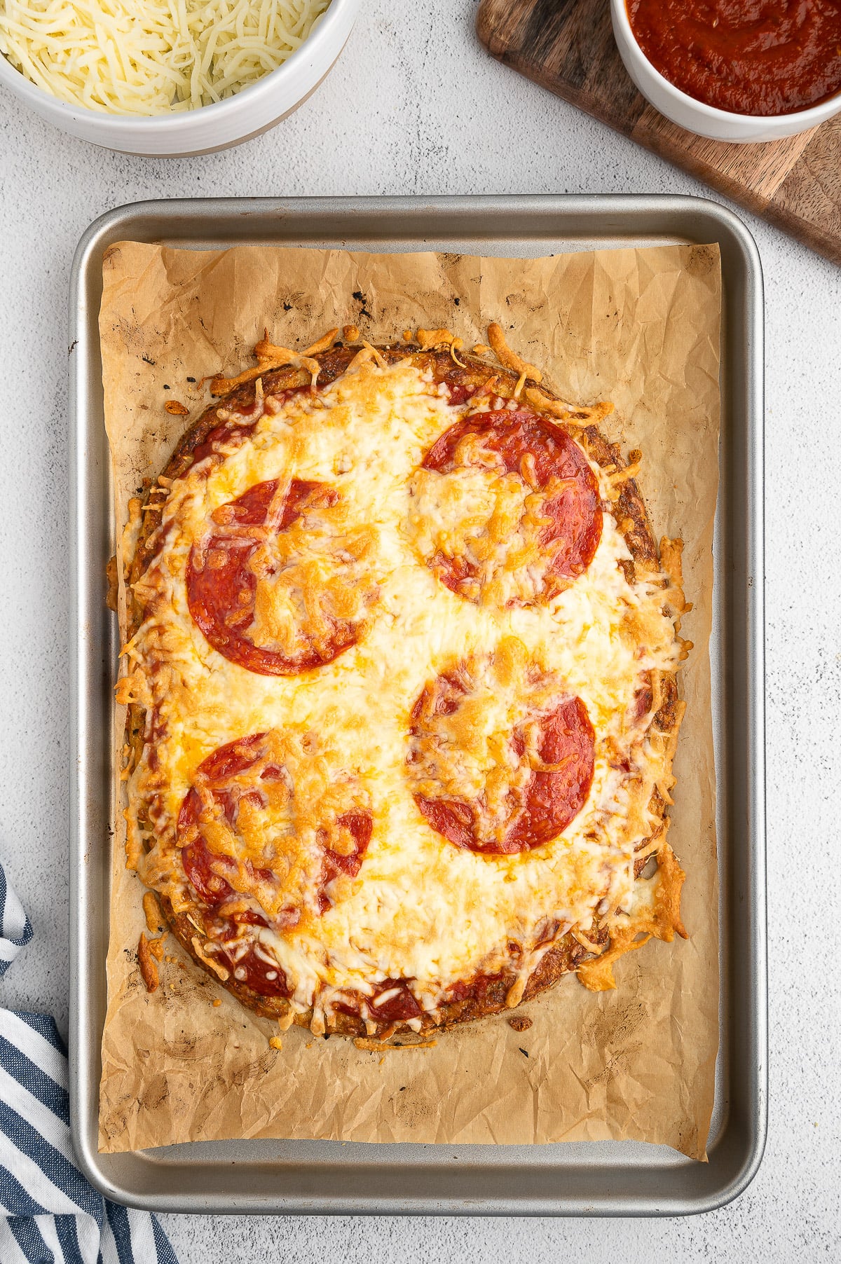 An overhead shot of a keto pizza with cauliflower pizza crust on a baking sheet