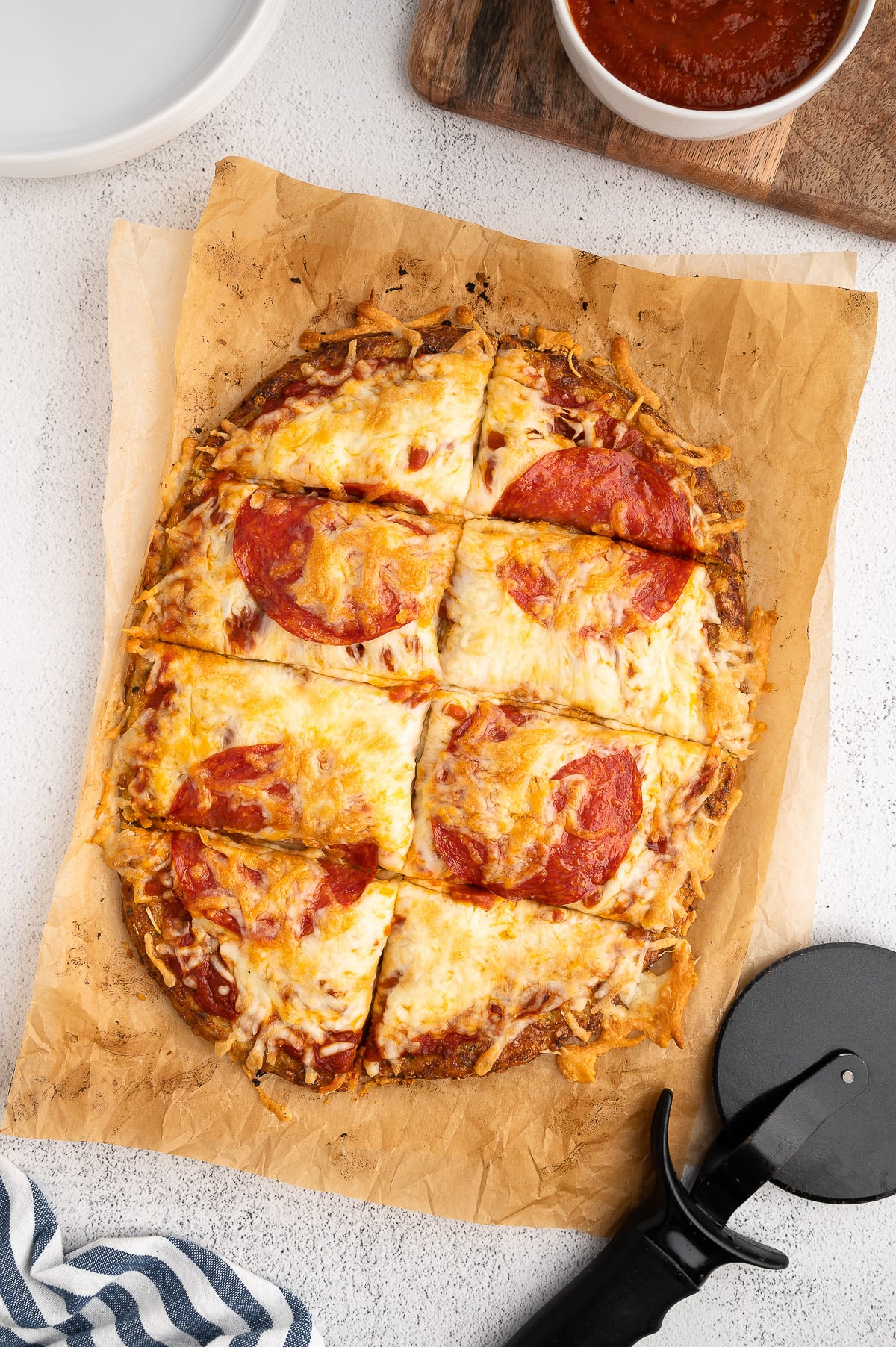 An overhead shot of a keto pizza with cauliflower pizza crust after being cut on a white background