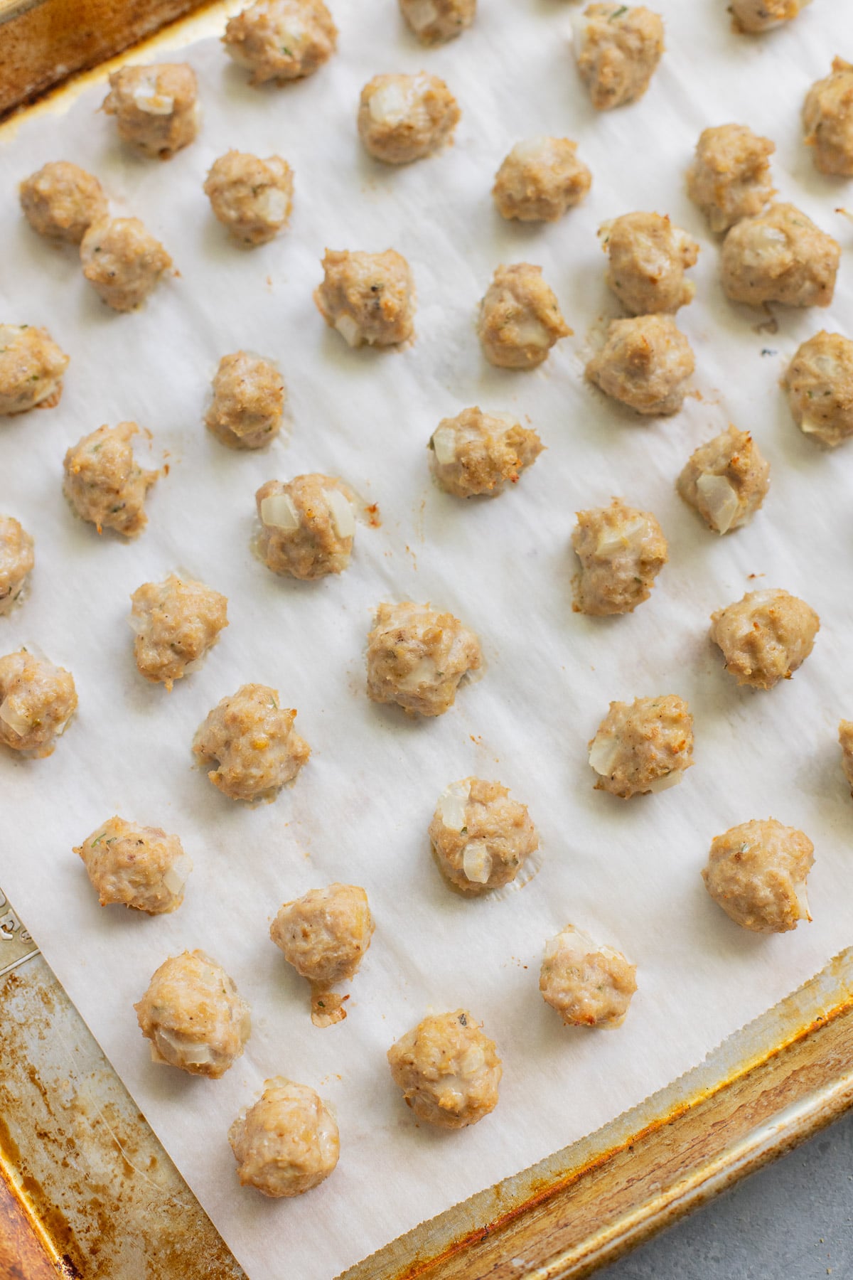 A baking sheet with lots of small meatballs for Italian wedding soup