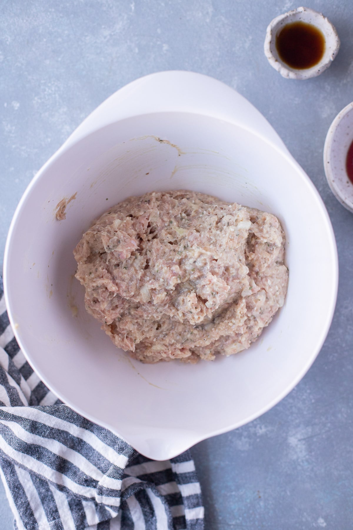 Ingredients for ground turkey meatloaf mixed together raw in a white bowl on a grey background