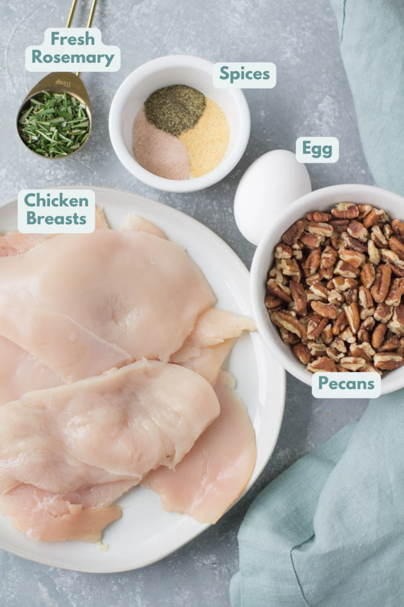 Ingredients for Pecan Crusted Chicken on a grey background with a blue linen off to the side.