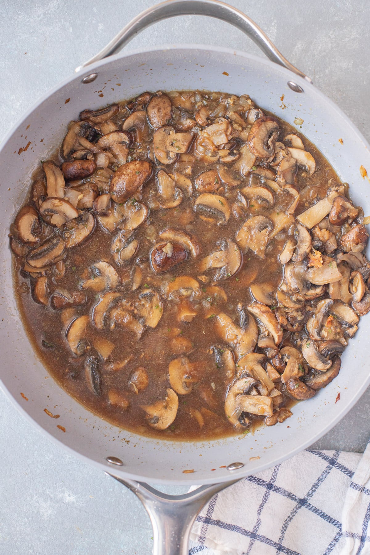 An overhead shot of marsala sauce for chicken marsala in a pan on a grey background