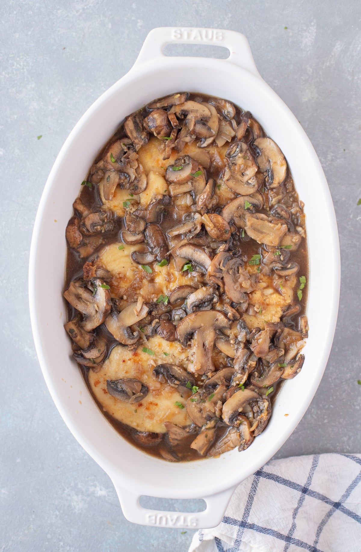 An overhead shot of a white baking dish of chicken marsala