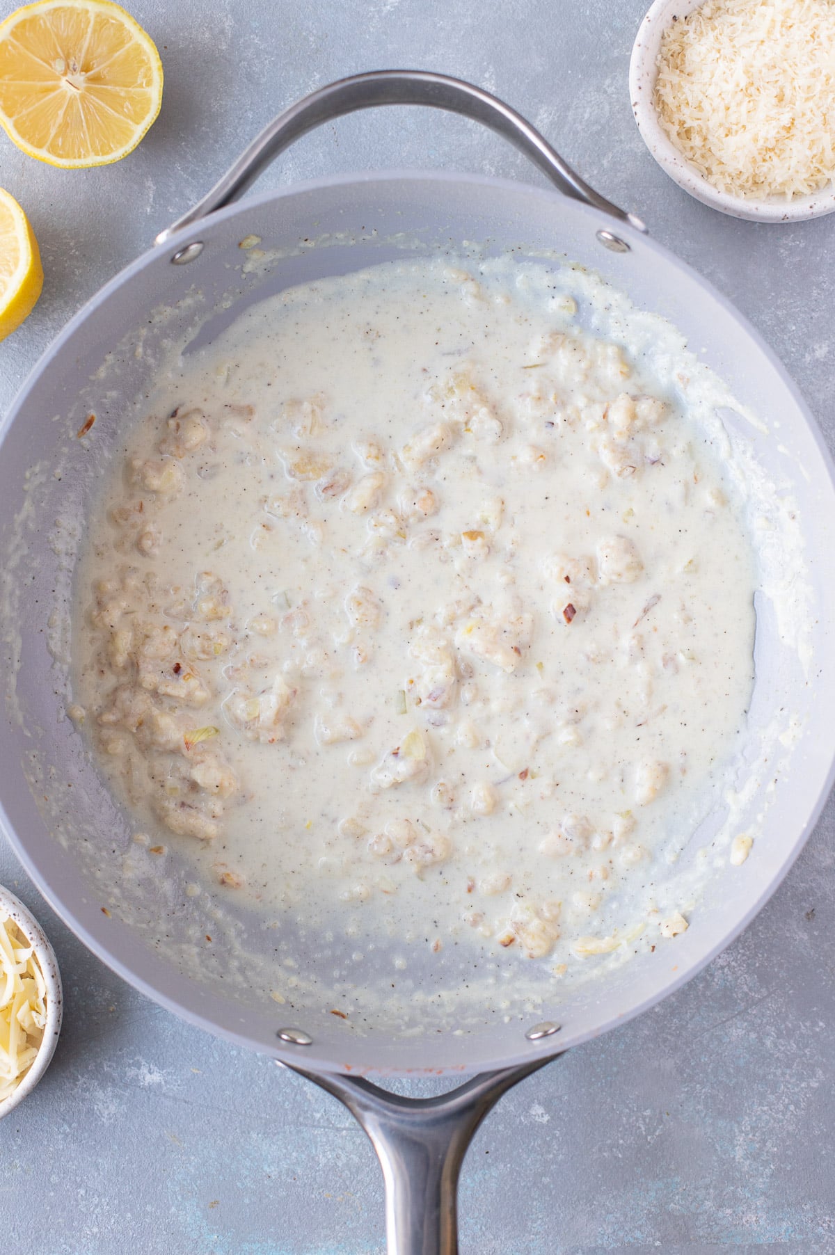 Onions and garlic cooking in a pan for creamy lemon pasta on a grey background