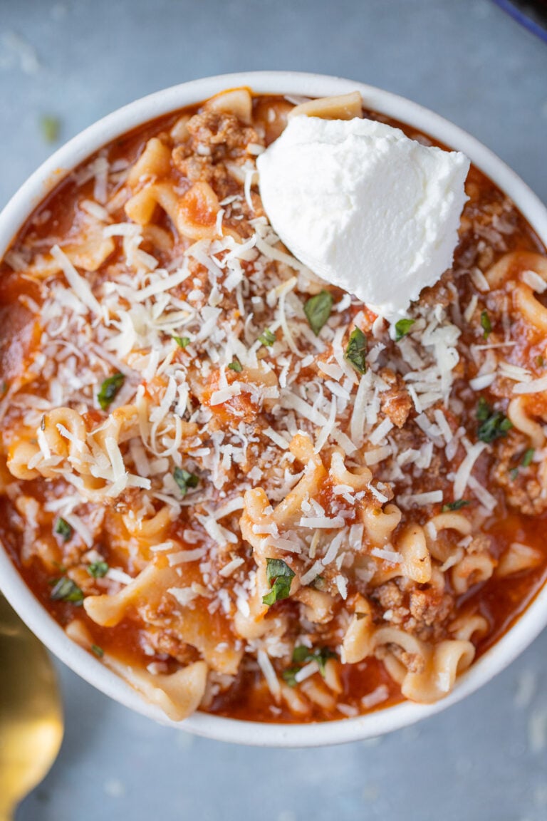 An overhead shot of lasagna soup with ricotta cheese on top on a grey background