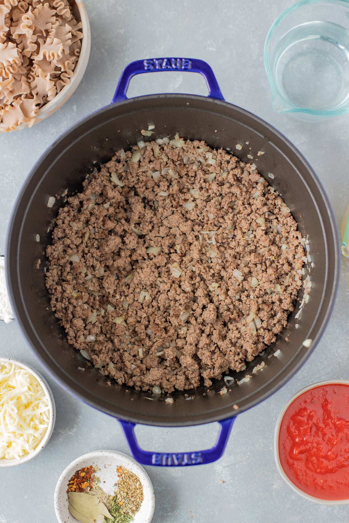 Ground beef, onions, and garlic after sauteing in a large pot on a grey background for lasagna soup