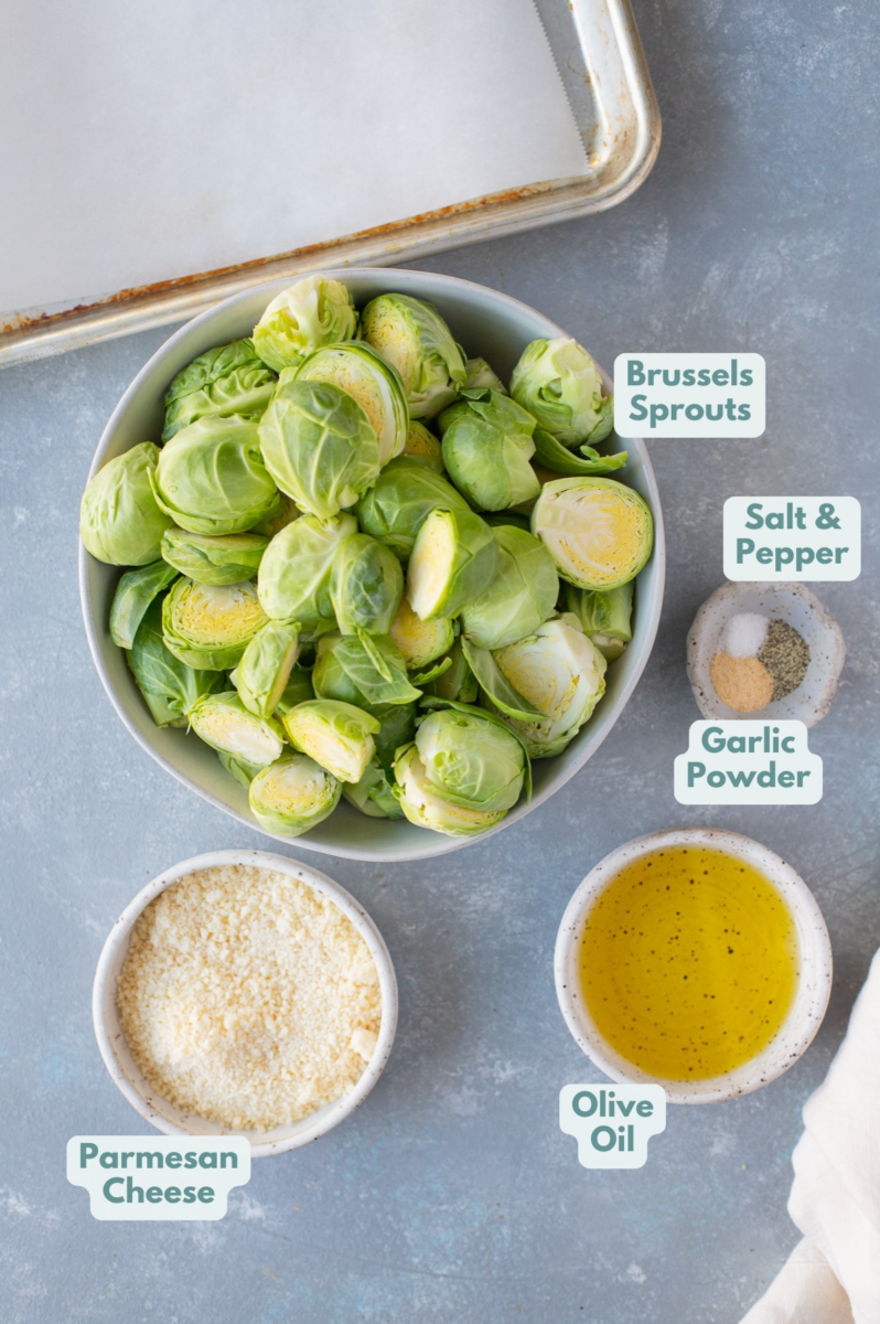 Ingredients for parmesan brussels sprouts in white bowls: brussels sprouts, olive oil, salt, pepper, garlic powder, parmesan cheese