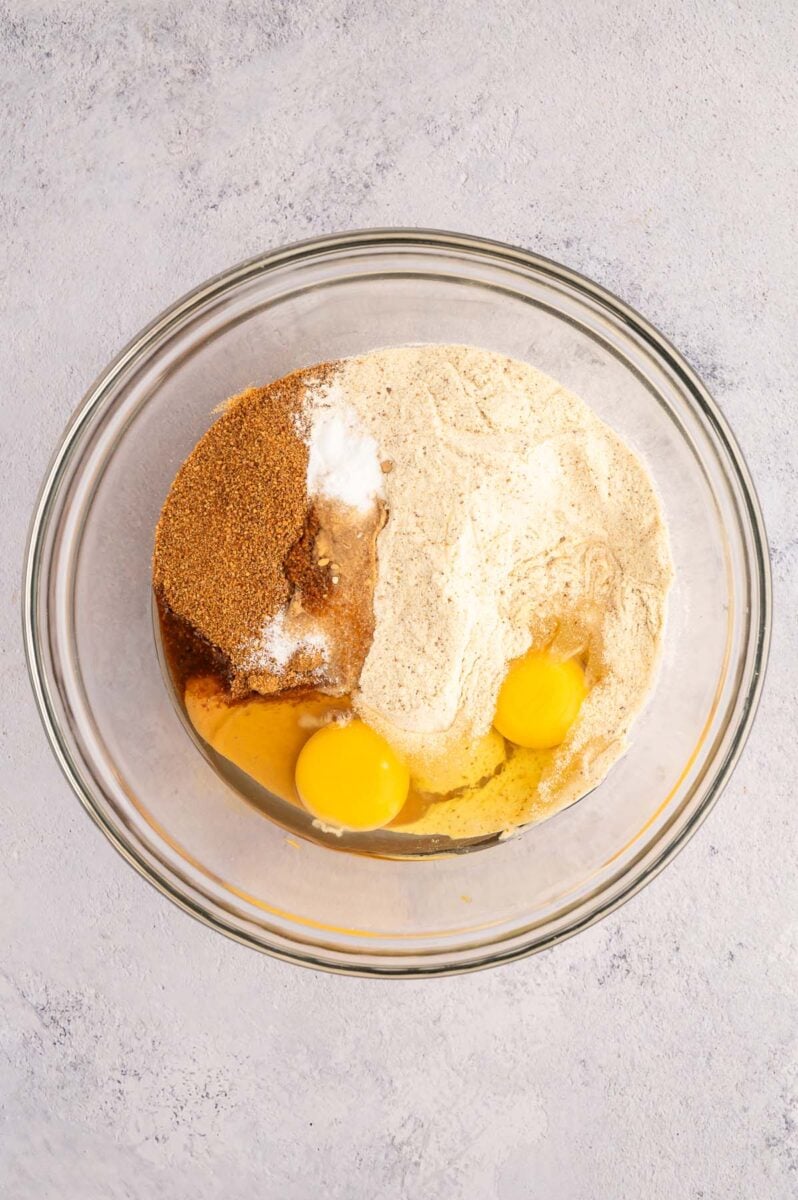 Ingredients for protein cookies in a clear bowl before being mixed together.