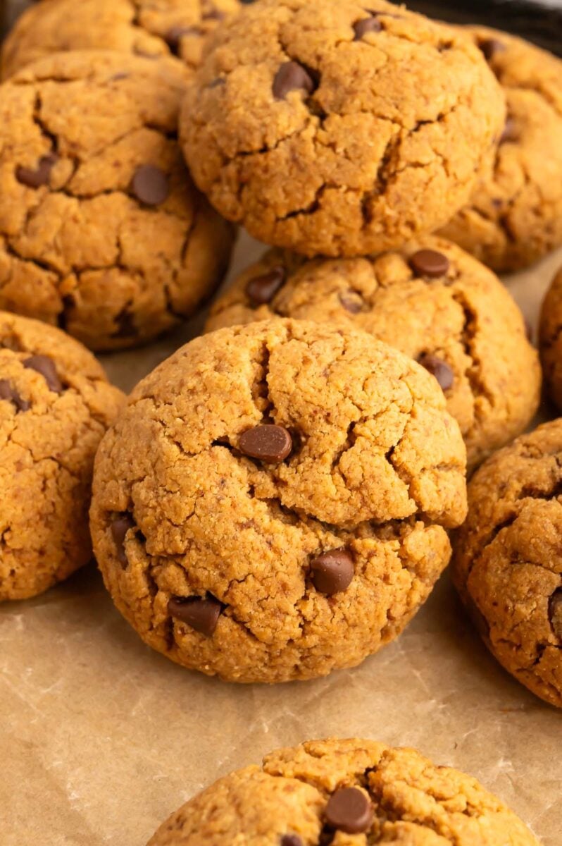 Protein cookies stacked in a pile on a piece of parchment paper.