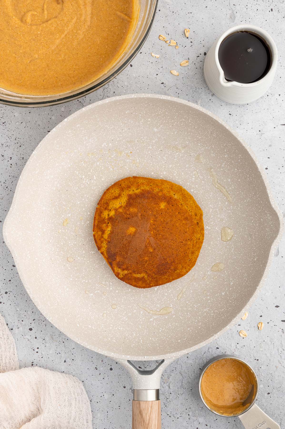 An overhead shot of a pan with a sweet potato pancake in it with more batter on the side