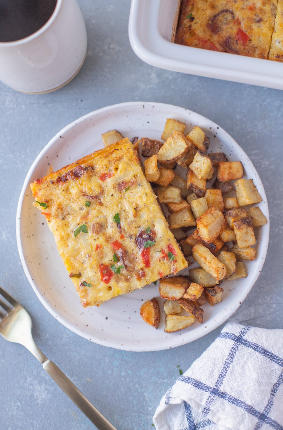 Plated serving of breakfast casserole with bacon and potatoes, as seen from overhead.