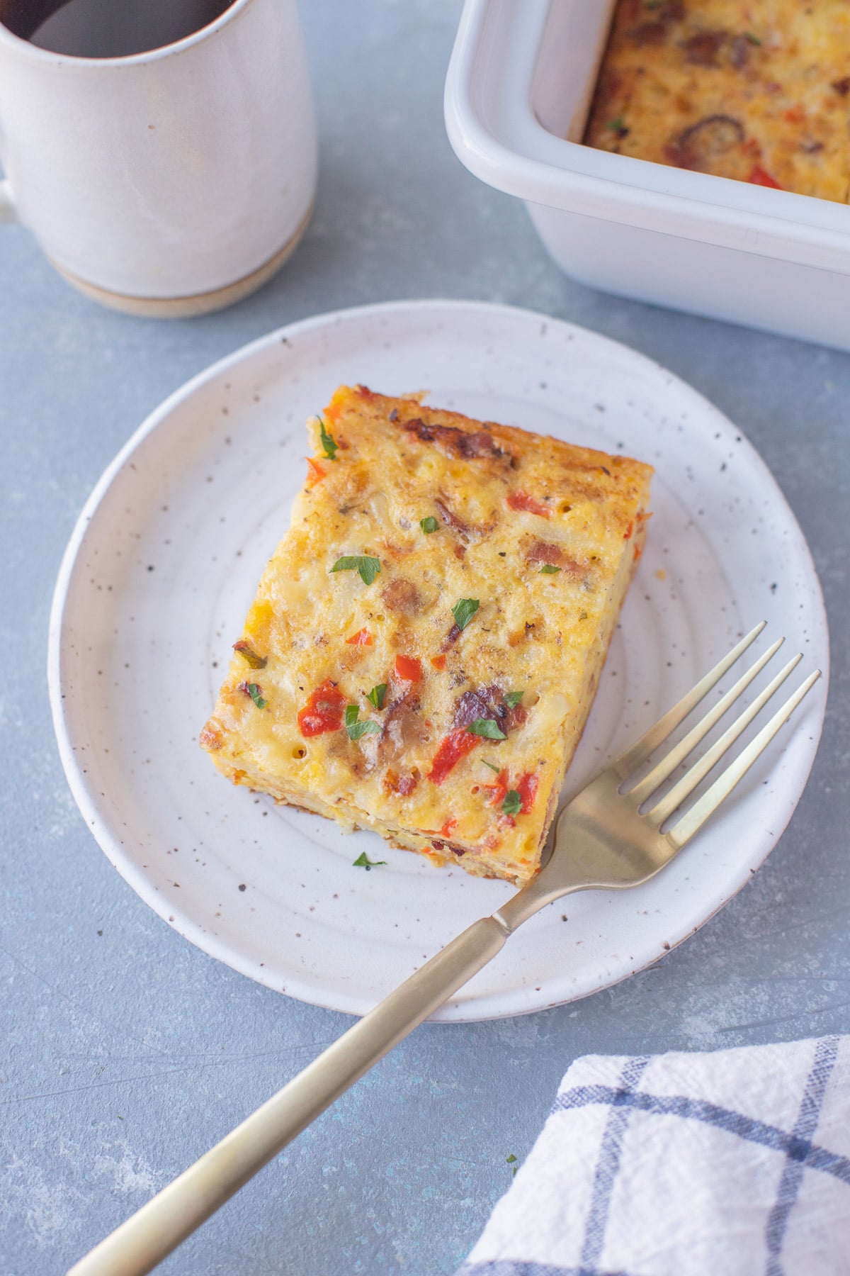 Plated serving of egg bake with cheese, bacon and potatoes.