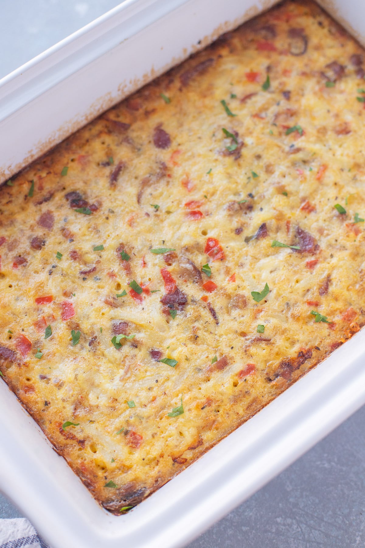 Breakfast casserole with bacon in a white casserole dish, viewed from overhead.
