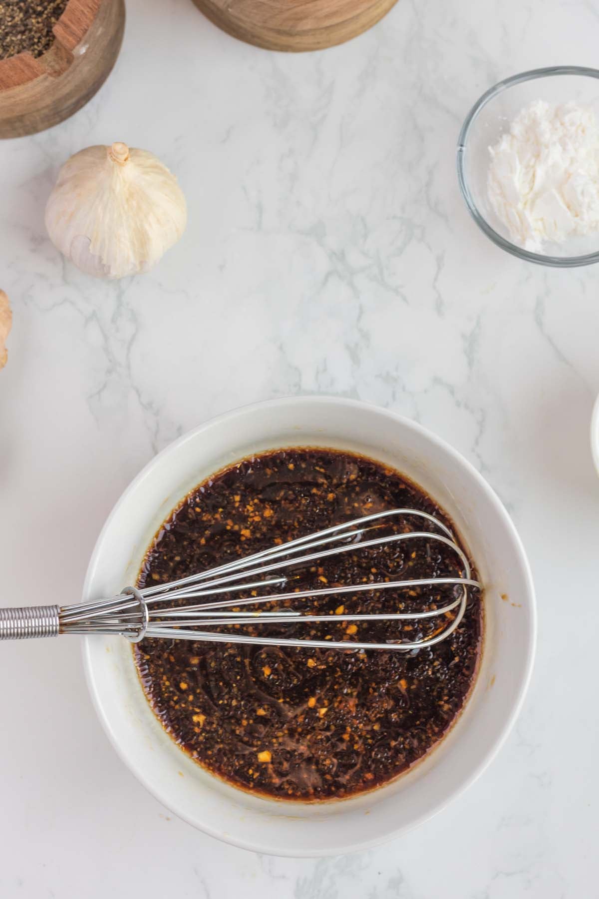 Teriyaki sauce being whisked for ginger chicken in a small white bowl on a white background