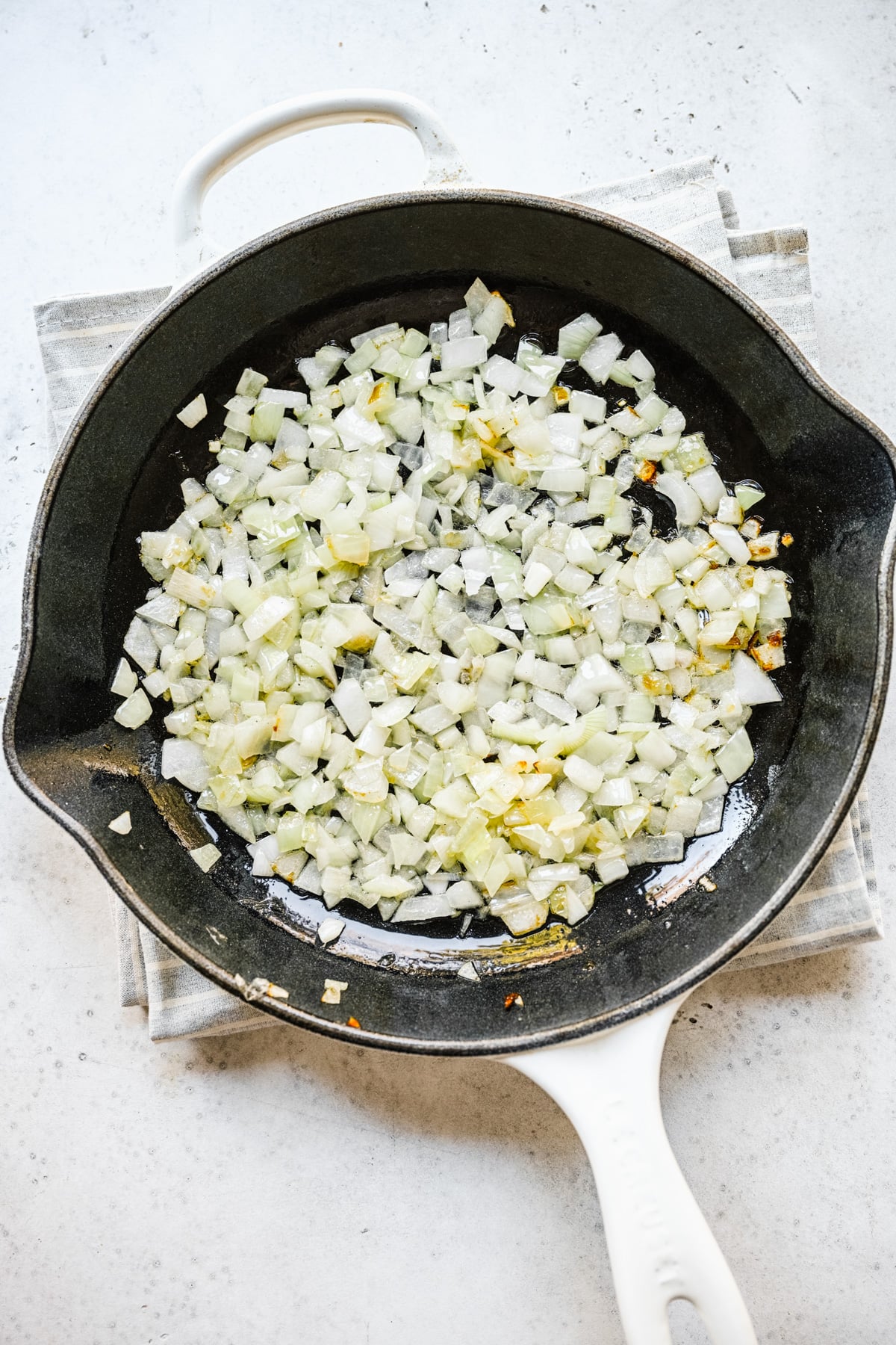 Onions cooking in a cast iron pan in butter, viewed from overhead