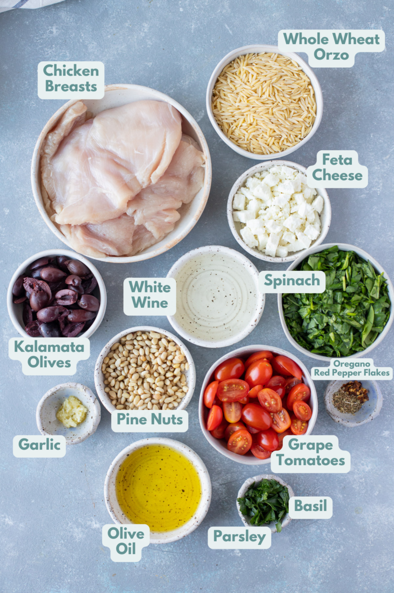 ingredients to make mediterranean chicken orzo: boneless chicken breasts, whole wheat orzo, pitted kalamata olives, pine nuts, tomatoes, spinach, olive oil, garlic, feta, herbs and spices (fresh basil, fresh parsley, pepper, oregano, red pepper flakes), white wine