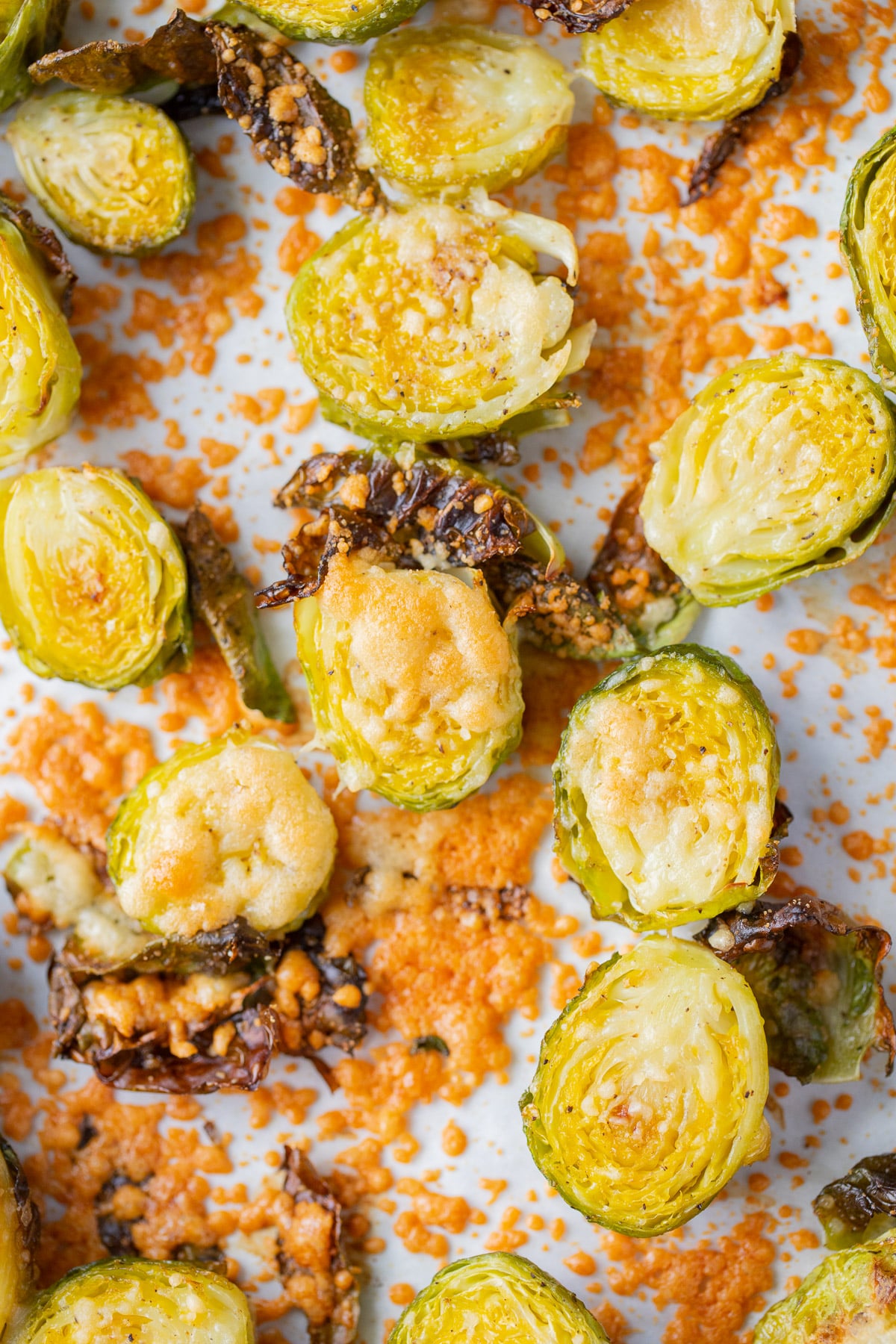 A close up of a parchment lined baking sheet with parmesan brussels sprouts on it
