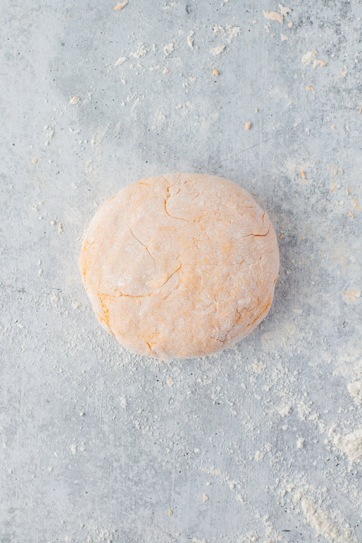 A sweet potato gnocchi dough ball on a floured counter