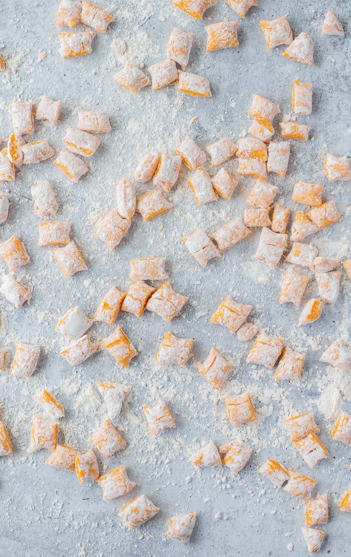 A lot of sweet potato gnocchi pieces on a floured surface