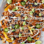 A sheet pan with loaded bell pepper nachos on a grey background