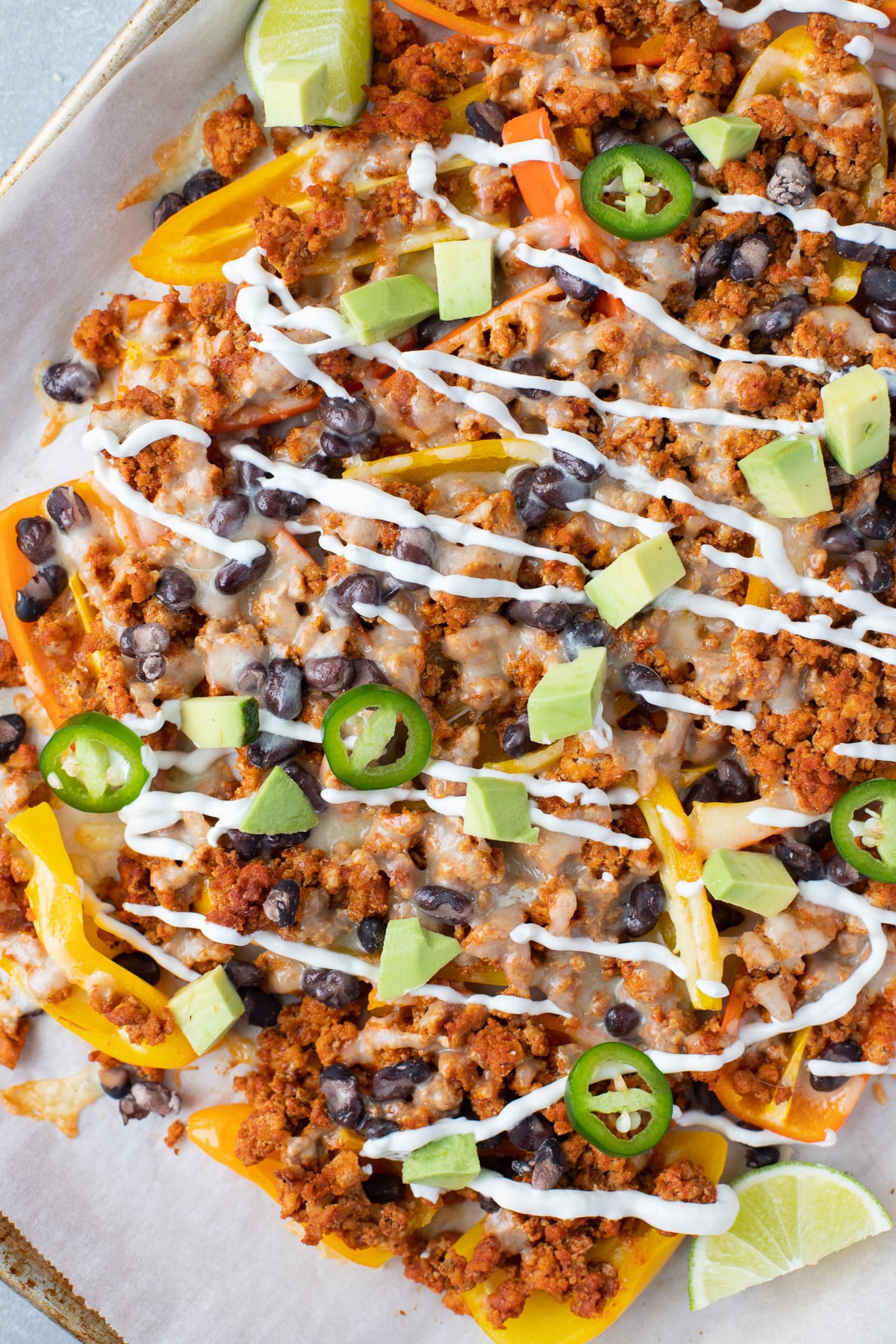 A sheet pan with loaded bell pepper nachos on a grey background