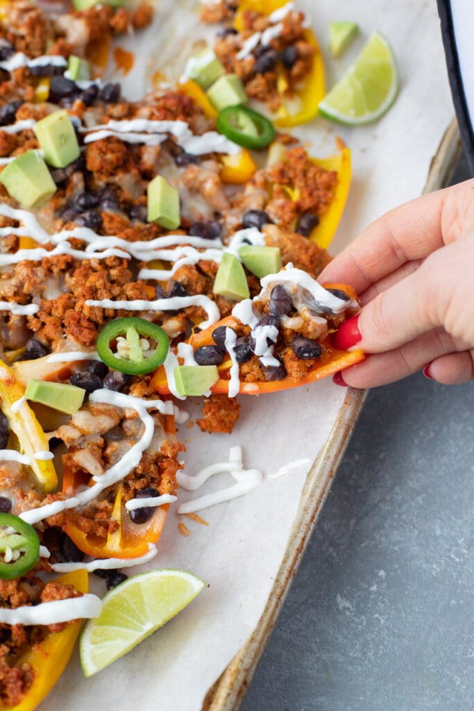 A bell pepper nachos being pulled away from the sheet pan of nachos