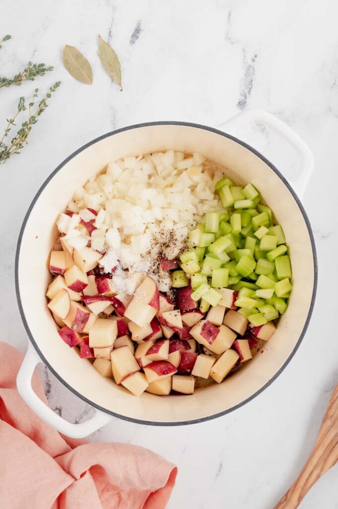 Onion, celery, potatoes, and spices in a stock pot to be cooked for chicken corn chowder