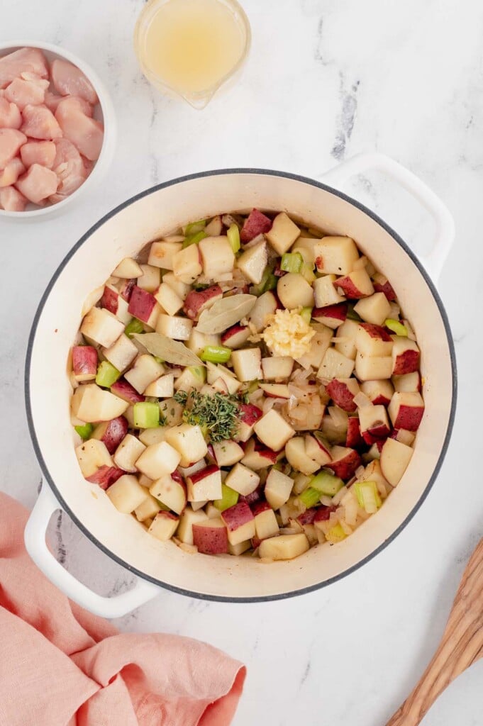 Spices added to a dutch oven with other ingredients for chicken corn chowder