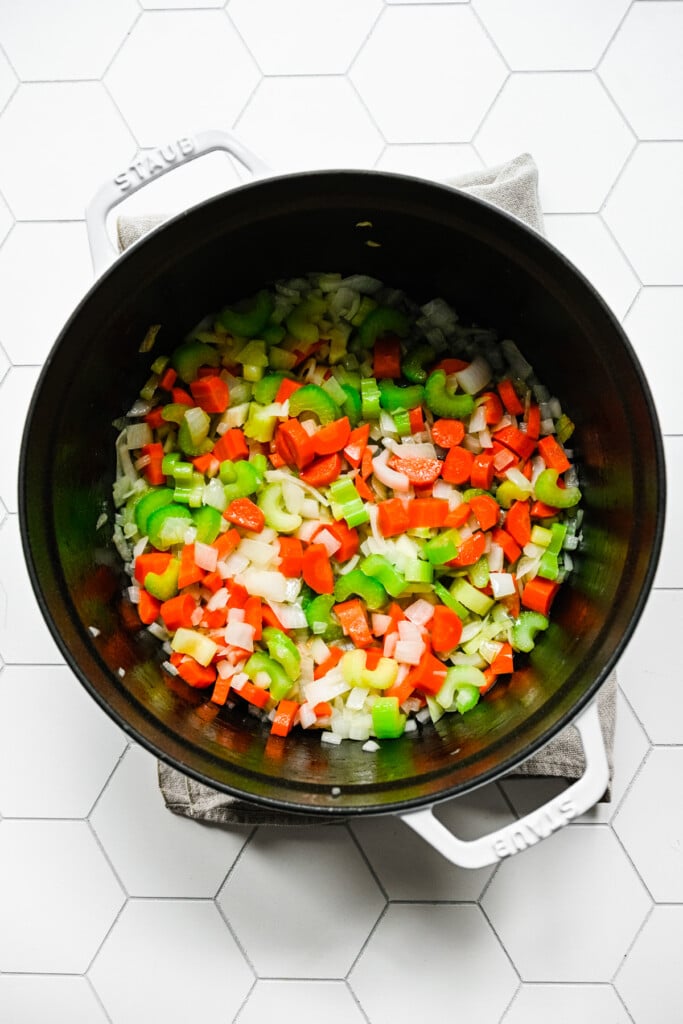 Onion, carrots, celery and garlic cooking in butter in a dutch oven for chicken tortellini soup