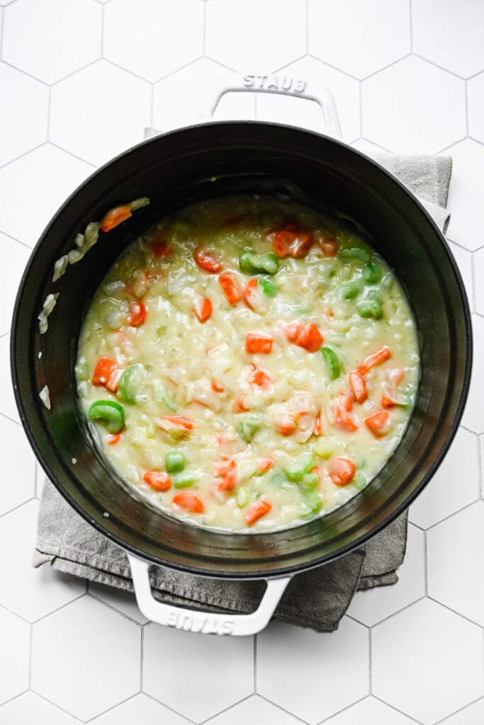 Onion, carrots, celery and garlic cooked in butter with flour and chicken broth added in a dutch oven for chicken tortellini soup