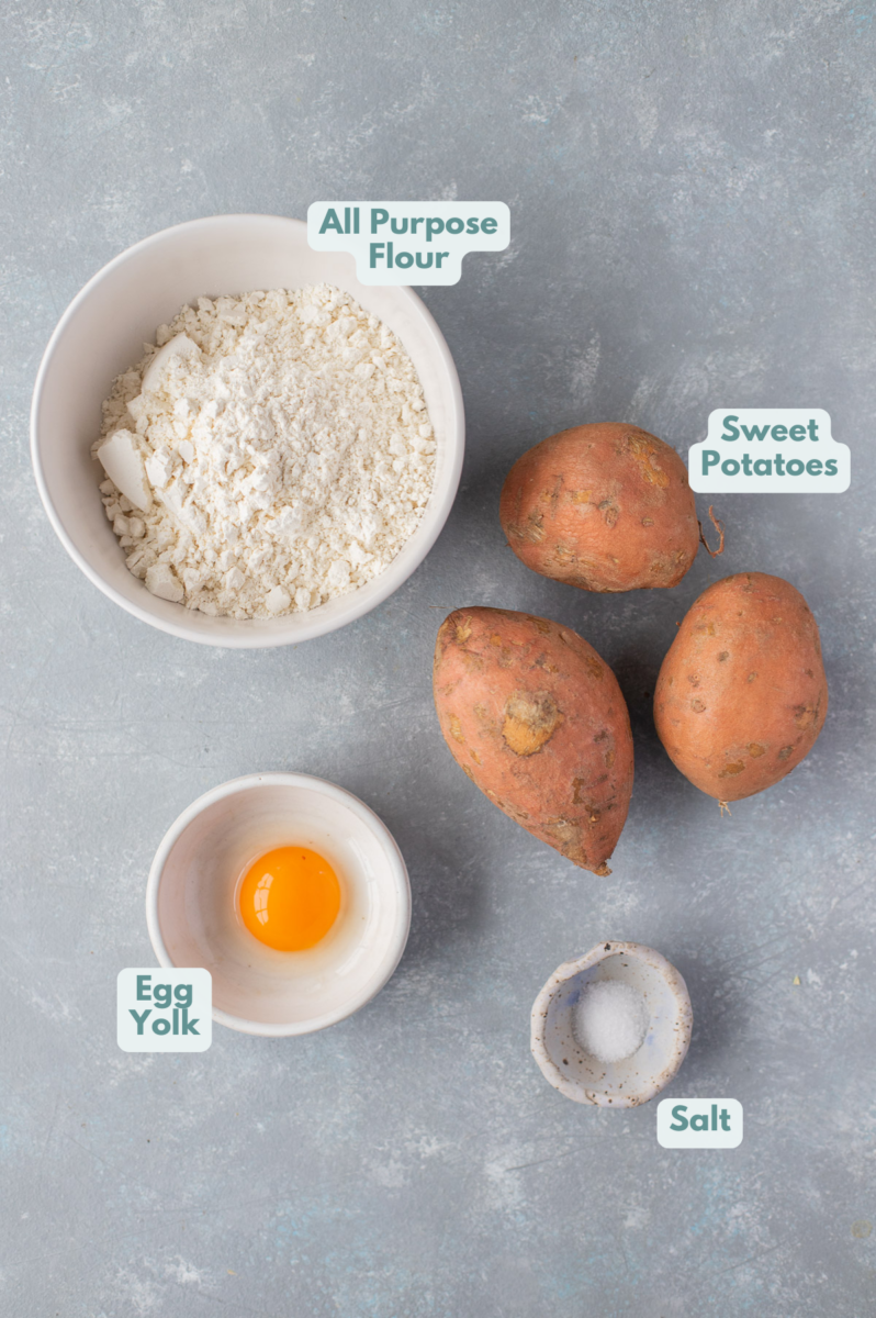 Ingredients for sweet potato gnocchi in white bowls: sweet potatoes, egg yolk, flour, sea salt