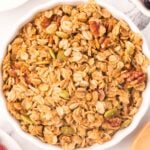 A white bowl of homemade granola on a white background