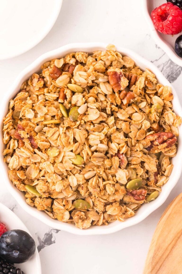 A white bowl of homemade granola on a white background