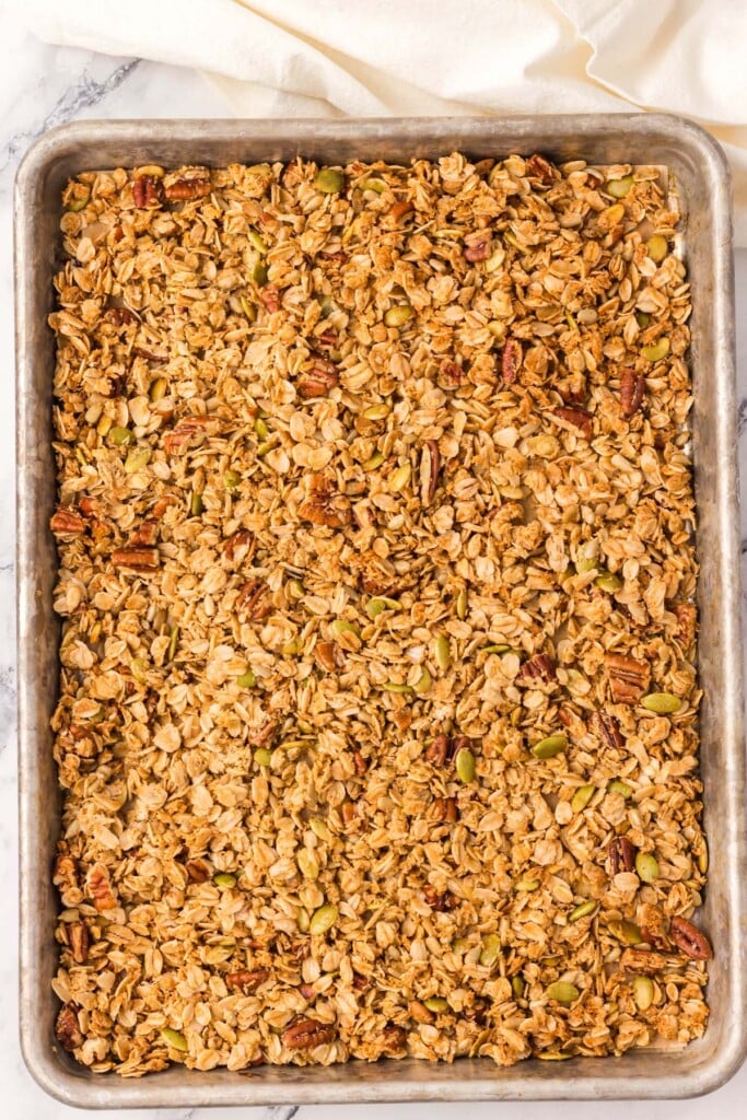 Homemade granola on a parchment lined baking sheet right after baking