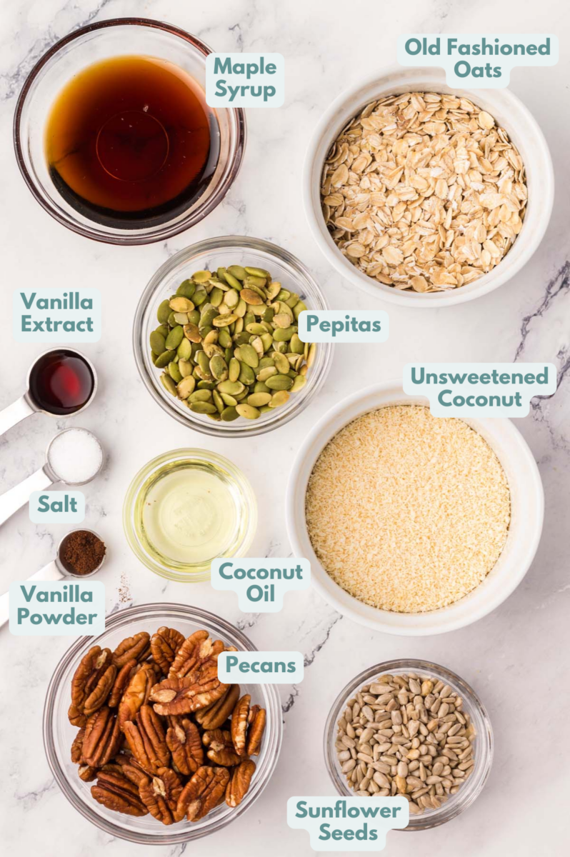 Ingredients for homemade granola in small bowls on a white background: rolled oats, unsweetened coconut, sunflower seeds, pepitas, pecans, vanilla powder, salt, maple syrup, coconut oil, vanilla extract