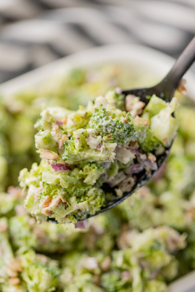 a close up of a spoon scooping a serving of the best broccoli salad