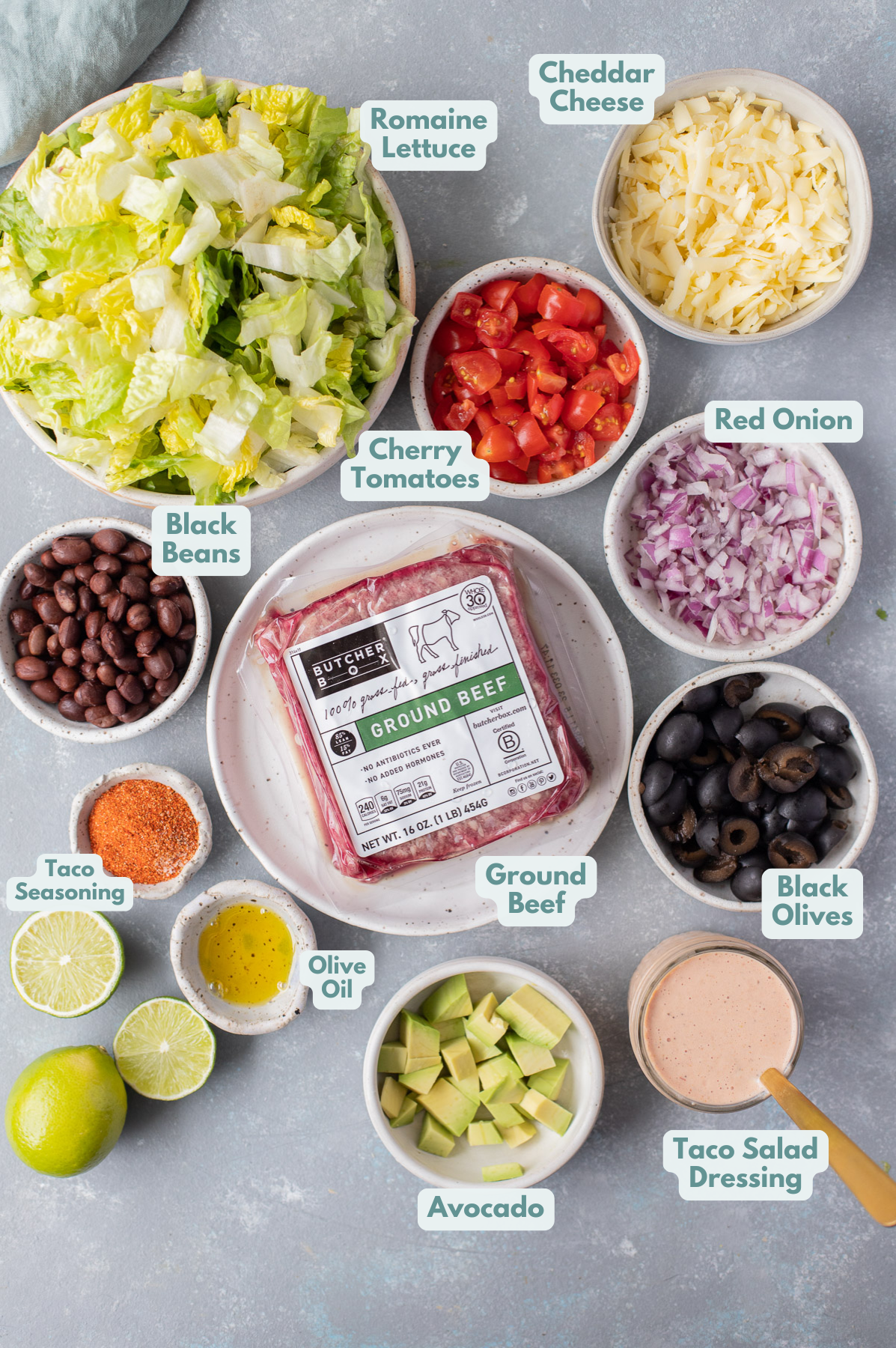 Ingredients for a healthy taco salad in small white bowls on a grey background, viewed from above.