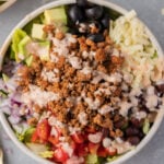 a close up of healthy taco salad in a white bowl on a grey background