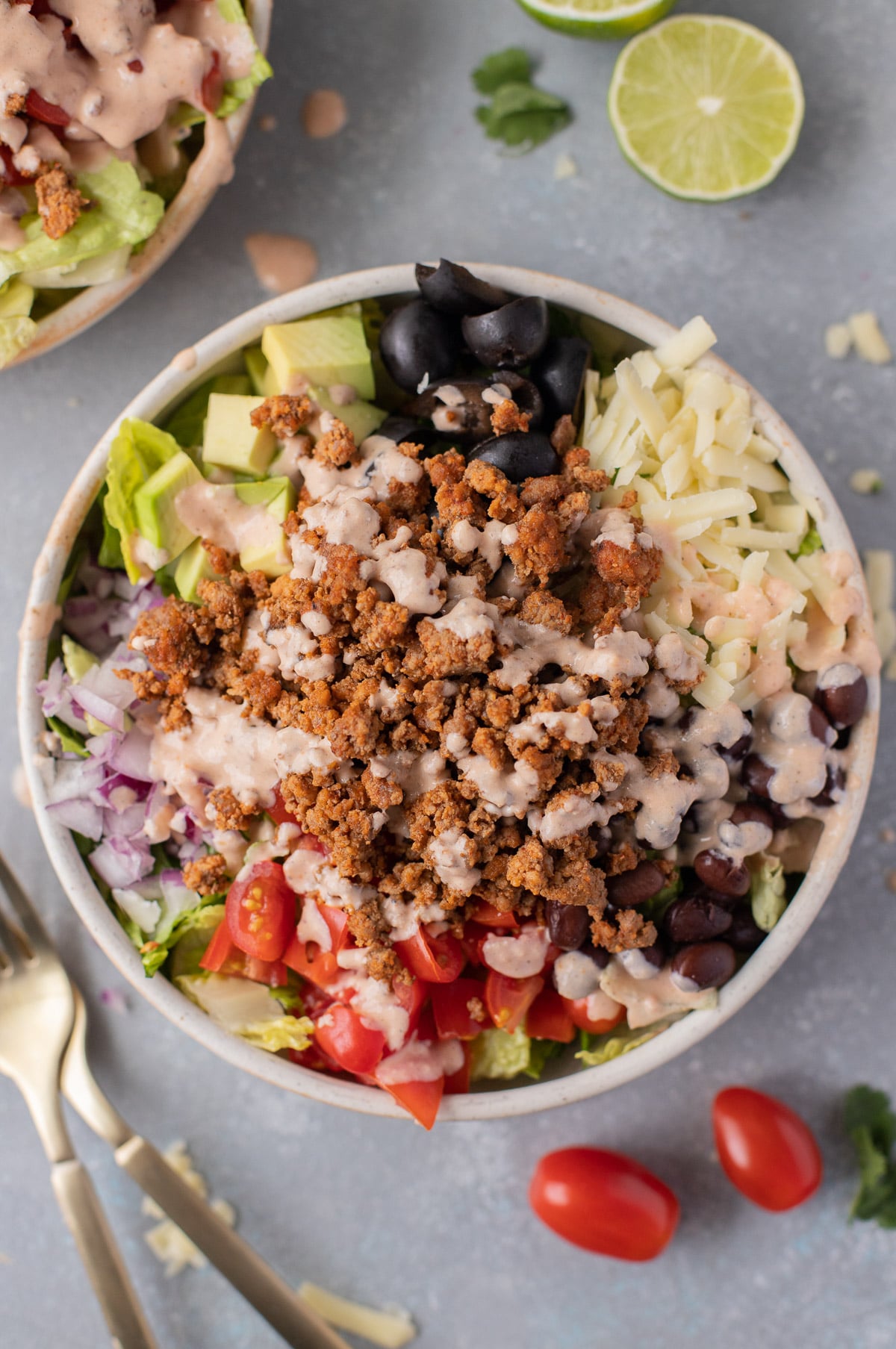 Overhead view of a Tex-Mex style ground beef dinner with shredded lettuce, diced vegetables, shredded cheese, and cooked ground meat in a large bowl.