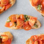 Homemade bruschetta on small baguette toasts on a grey background