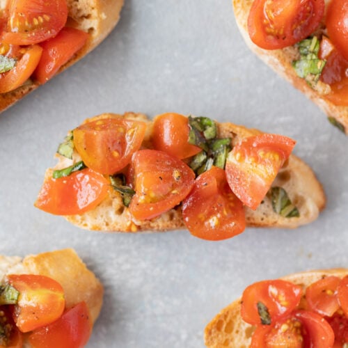 Homemade bruschetta on small baguette toasts on a grey background