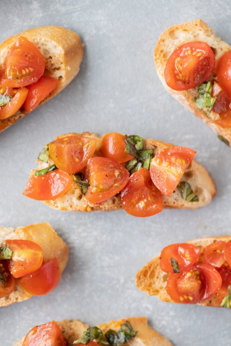 Homemade bruschetta on small baguette toasts on a grey background
