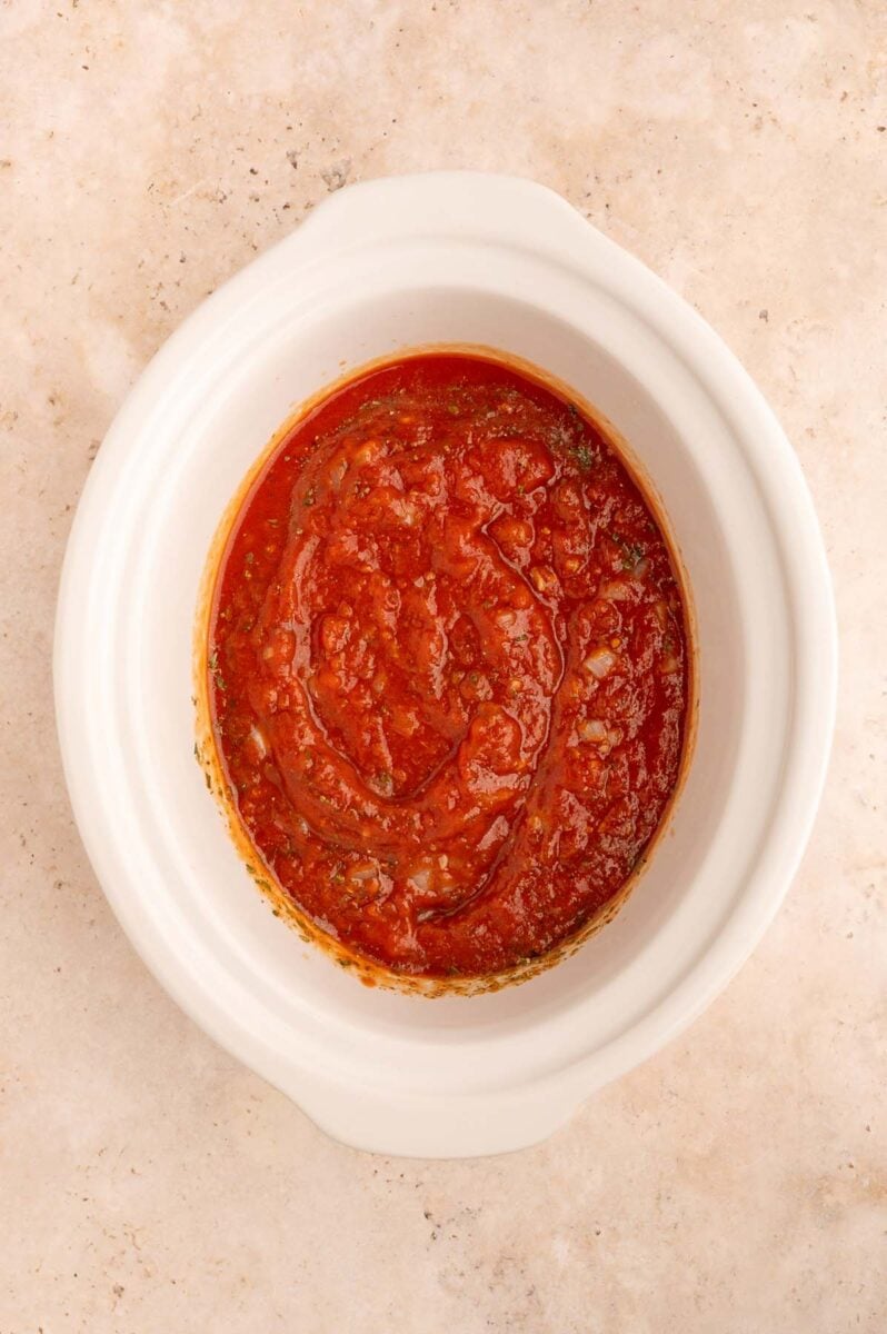 Crockpot tomato sauce in a white slow cooker base on a counter. 
