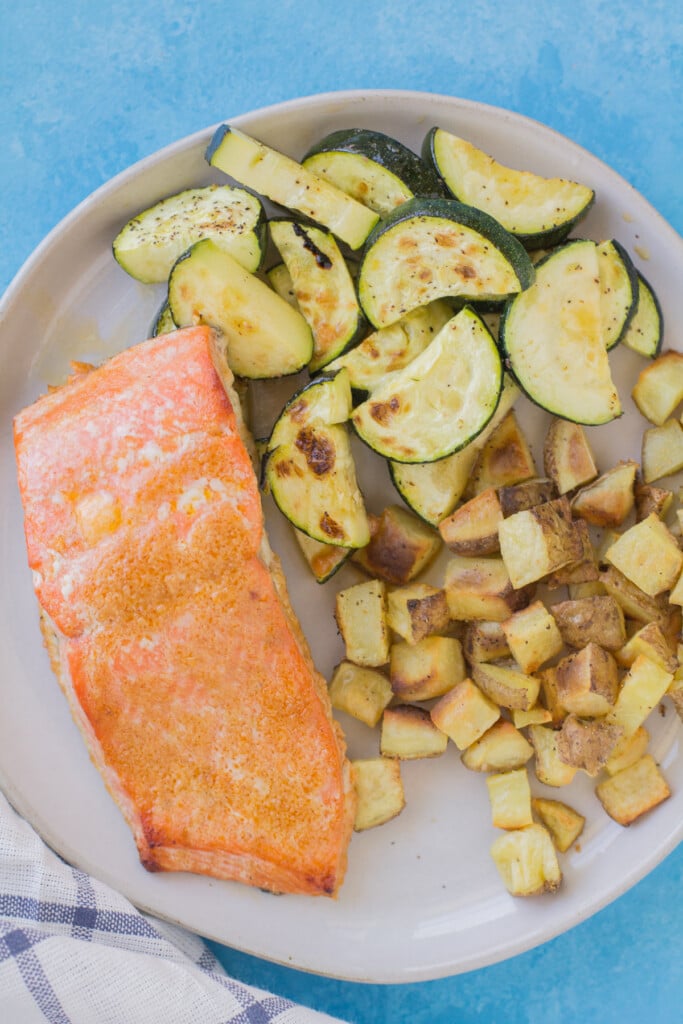 Salmon dinner idea - baked fish on a white plate with zucchini and diced potatoes