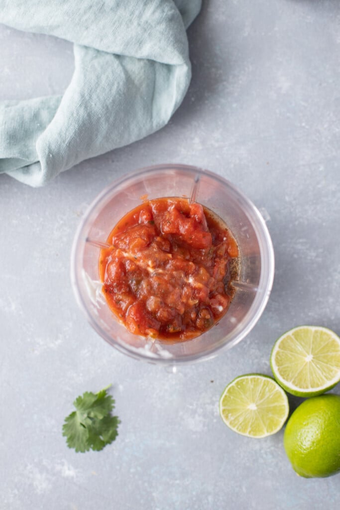 Ingredients for creamy salsa dressing in a small blender with sliced limes and cilantro on the side