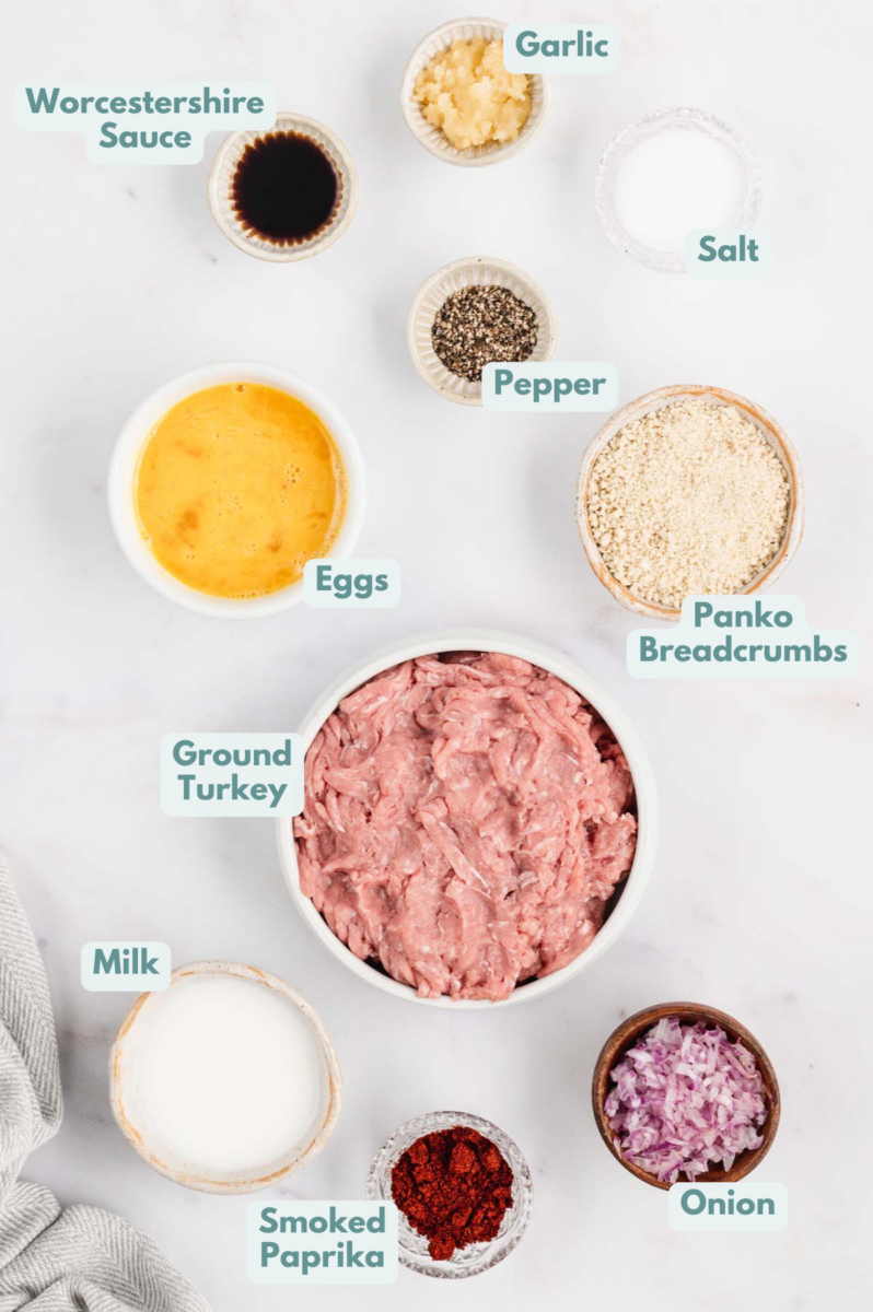 Ingredients for the best turkey burgers in white bowls on a white background: ground turkey, panko bread crumbs, eggs, milk, yellow onion, garlic, worcestershire sauce, pepper, salt, smoked paprika