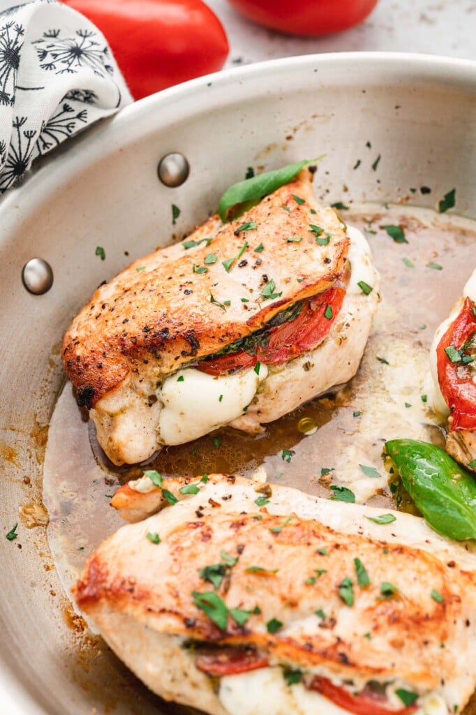 Chicken caprese cooking in an oven safe skillet,